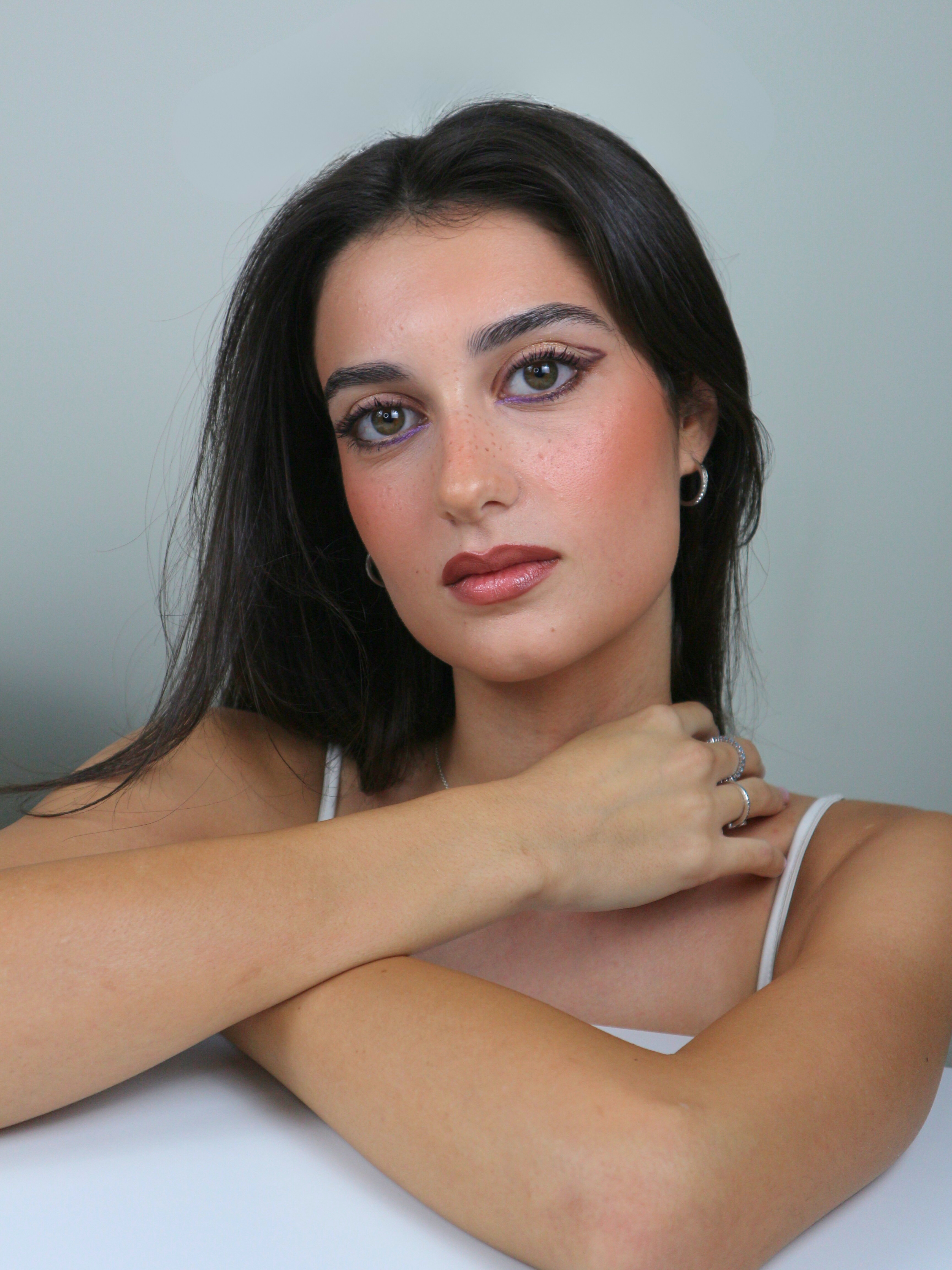 Graphic eyeliner with a pop of lilac, natural skin that highlights freckles, and soft rosy nude lips for a fresh and sophisticated look. A radiant makeup that blends boldness with delicacy.